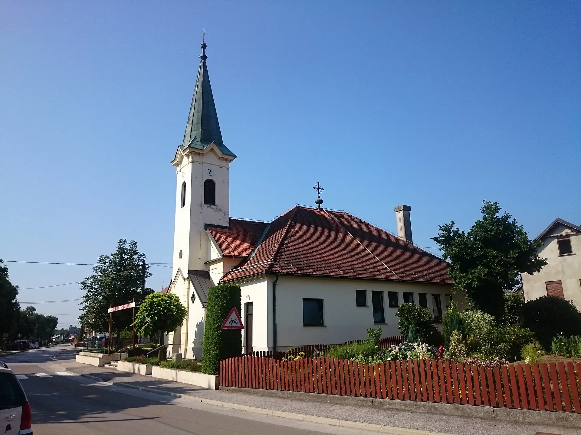 Pfarrkirche St. Anna in Bakovci mit spitzem Turm und Pfarrhof